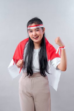 Bağımsızlık Günü 'nde heyecan ve milli gurur gösteren neşeli Endonezyalı genç kadın. Kırmızı ve beyaz aksesuarlarla, kendine güvenen bir şekilde poz verir ve gülümser..