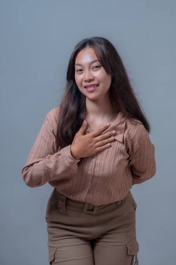 Kendine güvenen Endonezyalı bir kadın içten bir gülümsemeyle elini göğsüne koyuyor. Minnettarlık veya samimiyet göstergesi olarak..