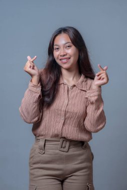 Endonezyalı genç bir kadın gülümsüyor ve iki eliyle 