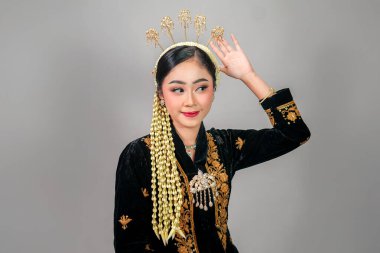 Geleneksel Cava kıyafeti giyen zarif bir Asyalı kadının portresi, büyüleyici bir ifadeyle gülümsüyor, karmaşık altın aksesuarlar ve yasemin çiçekleri ile süslenmiş..