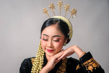 Altın işlemeli geleneksel Cava kıyafetleri ve çiçek aksesuarları giyen Asyalı kadın zarif gülüşü ve huzurlu gözleriyle zarafetini ve dinginliğini ifade ediyor..