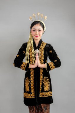 Geleneksel Java kebaya 'sı olan Asyalı kadın saygılı bir jest yaparken nazikçe gülümsüyor, kültürel zarafet, güzellik ve etnik gurur sergiliyor..