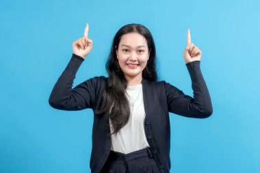 Gülümseyen kadın her iki işaret parmağını da mavi arka plana doğru kaldırarak fotokopi alanını öne çıkarıyor. İş, reklam ve tanıtım içeriği için ideal.