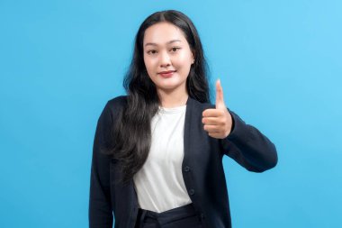 Gülümseyen kadın mavi arkaplan karşısında baş parmak hareketi yapıyor. Onaylama, pozitiflik ve başarı gösteriyor. Anlaşma, teşvik veya müşteri memnuniyeti kavramları için ideal.