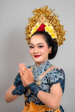 Modern Balili geleneksel elbiseli Asyalı kadın zarif bir gülümseme ve ellerini birbirine bastırarak poz veriyor, zarafetini, iç huzurunu ve huzurlu bir portreye duyduğu güveni ifade ediyor..