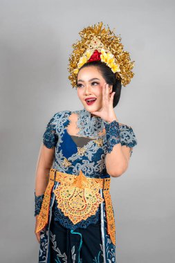 Çağdaş Balili elbiseli güzel bir Asyalı kadın. Çiçekli taç ve altın aksesuarlı. Parlak gözleriyle şaşkınlığını ve neşesini ifade ediyor..