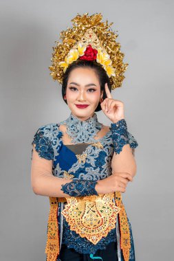 Modern Bali geleneksel giysileri, zarif dantel kebaya, karmaşık altın taç ve kültürel veya reklam kavramları için anlamlı poz giyen kendine güvenen Asyalı bir kadın..