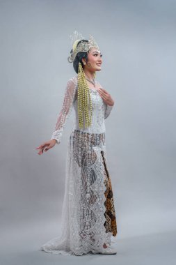 Geleneksel Sundan kılığına girmiş gülümseyen Endonezyalı bir gelinin tüm vücut portresi süslenmiş dantel kebaya, batik etek, siger taç ve zarif duruş içinde uzun yasemin çelenkler..