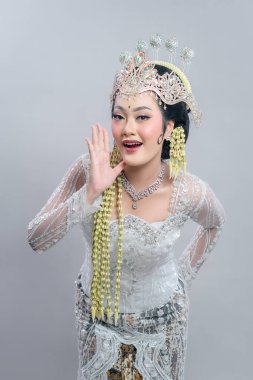 Endonezyalı neşeli bir gelin geleneksel Sundan kıyafetleriyle neşeli bir jest yapıyor. Parlak kebaya, karmaşık taç ve yasemin aksesuarları zarafeti ve kültürel güzelliği ön plana çıkarıyor..