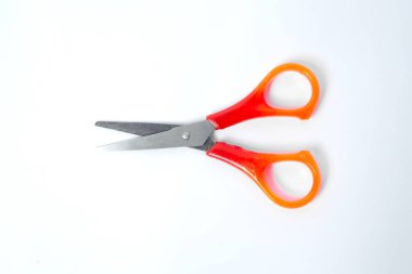 Beyaz arka planda izole edilmiş keskin çelik bıçaklı parlak turuncu plastik saplı makas, ofis, okul ve el işi araçlarının sembolü.