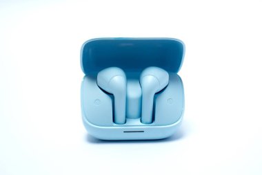 Şarj kutusu beyaz arka planda olan mavi kablosuz kulaklıklar, yaşam tarzı, müzik, eğlence, iş ve günlük mesleki kullanımda iletişim için modern ses teknolojisi.