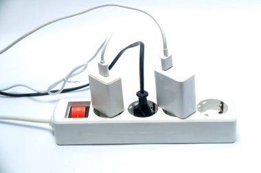 Kırmızı düğmeli beyaz güç şeridi, siyah fişi ve beyaz arka planda izole edilmiş iki beyaz kabloya bağlı iki beyaz şarj aleti, elektrik, enerji, iş, teknoloji ve ev kullanımının sembolü.