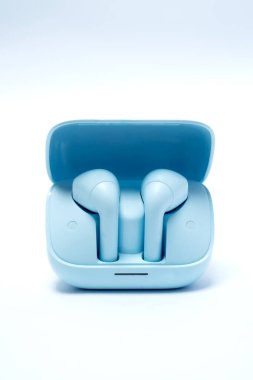 Mavi şarj çantasındaki modern kablosuz kulaklıklar, beyaz arka planda izole edilmiş, müziği, yaşam tarzını, teknolojiyi ve taşınabilir ses kolaylığını simgeliyor.