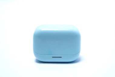 Kapalı mavi kablosuz kulaklık şarj kutusu beyaz arka planda, taşınabilir ses teknolojisini, modern yaşam tarzını, dijital müziği ve şık elektronik aksesuarları temsil ediyor..