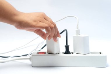 Elektrik prizinden elektrik, enerji, teknoloji, güvenlik, günlük yaşam ve modern yaşam tarzını temsil eden elektrik prizlerinin fişini çeken bir insan eli..