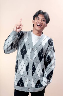 Gri baklava desenli hırka giyen Asyalı bir adam, güveni, mutluluğu, motivasyonu ve yeni fikirler kavramını göstererek parıl parıl gülümsüyor..