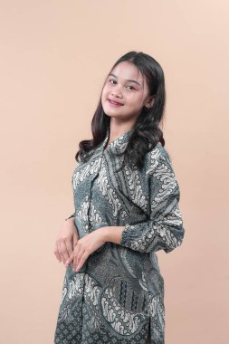 Zarif batik elbise içinde gülümseyen genç bir Asyalı kadın zarif bir poz veriyor, güzellik, cazibe ve kendine güveni doğal kültürel ifadeyle gösteriyor..