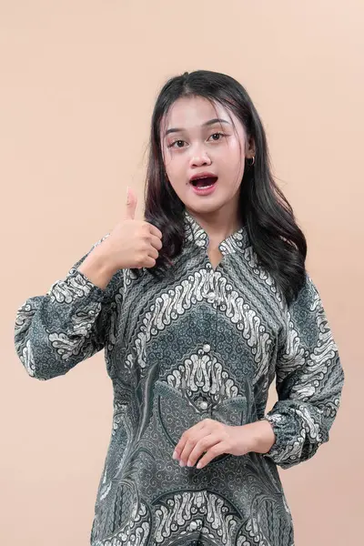 Zarif batik elbiseler giyen Asyalı kadın şaşırmış yüz ifadesini, pozitifliği, güveni ve kültürel gururu sembolize ediyor..