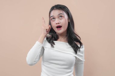 Beyaz omuzlu Asyalı kadın şaşırmış bir ifadeyle yukarıya doğru bakıyor, yeni fikirleri, iş ilhamını, motivasyonu, yaratıcılığı ve başarıyı simgeliyor..