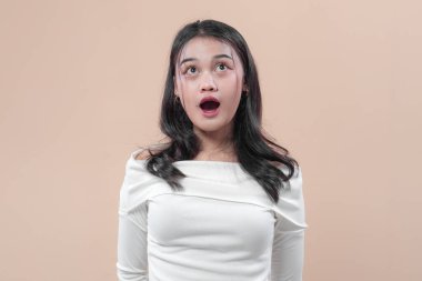 Beyaz omuzlu Asyalı kadın şaşırmış bir ifade, ağzı açık ve yukarı bakan gözler, şoku, şaşkınlığı, yaratıcılığı, duyguyu ve ilhamı simgeliyor..