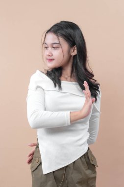 El hareketleriyle poz veren Asyalı genç bir kadın. Günlük beyaz bluz giyiyor. Reddettiğini, uyardığını, kendine güvenini ve vücut dilini ifade ediyor..