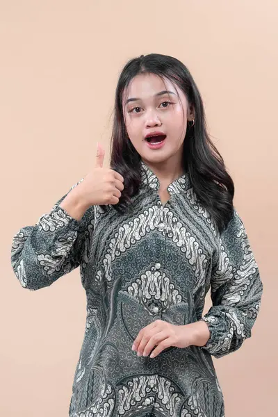 Zarif batik elbiseler giyen Asyalı kadın şaşırmış yüz ifadesini, pozitifliği, güveni ve kültürel gururu sembolize ediyor..