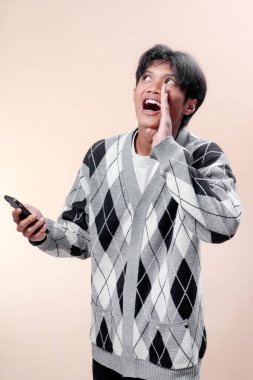 Asyalı adam akıllı telefonu tutarken, eli ağıza yakın, iletişim, heyecan ve iş, yaşam tarzı ve reklam kavramına güven gösteren anlamlı bir jest yapıyor..