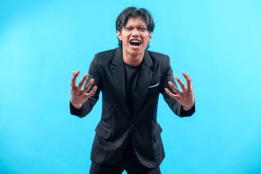 Siyah takım elbiseli Asyalı bir adam güçlü bir duygusal ifade sergiliyor. Elleri açık, stres, öfke ve hayal kırıklığını sembolize ederken yoğun ve dramatik enerjiyi yansıtıyor..