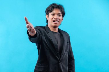 Siyah takım elbiseli genç bir adam, kendine güvenen bir ifadeyle, parlak mavi bir arkaplan karşısında gülümseyerek liderliği, iletişimi ve pozitifliği sembolize ediyor..