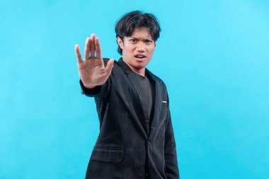 Siyah takım elbiseli genç adam ciddi bir yüz ifadesiyle elini kaldırıyor. Durma hareketi, uyarı, otorite ve profesyonel tutumu simgeliyor..