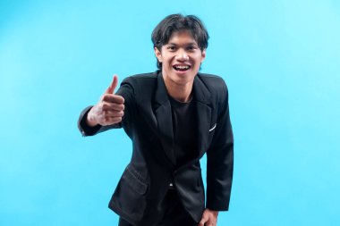 Siyah takım elbiseli kendine güvenen genç bir Asyalı, onay, coşku ve pozitif enerjiyi profesyonelce ifade eden bir jest gösterirken ışıl ışıl gülümser..