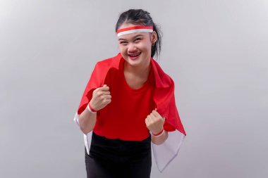 Genç Endonezyalı kadın Bağımsızlık Günü 'nü tutkuyla ve neşeyle kutluyor. Yumruk pozisyonunda kırmızı ve beyaz elbiseler giymek, gücü, gururu ve özgürlüğü simgeliyor..