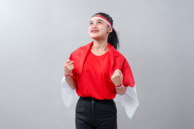 Kırmızı ve beyaz kıyafetli iyimser Endonezyalı kız sevinçle bakıyor ve yumruklarını sıkıyor. Bağımsızlık Günü 'nü kutlarken ruhuna ve gururuna ışık saçıyor.
