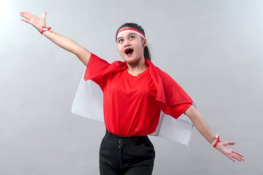 Neşeli Endonezyalı kız Bağımsızlık Günü için gurur ve heyecan ifade ediyor. Kırmızı ve beyaz kollarını açmış, vatansever ruhunu canlı bir şekilde gösteriyor..