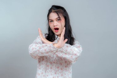 Ağzı açık genç Asyalı bir kadının iki koluyla X hareketi yapması, yoğun ve net bir yüz ifadesiyle reddedilmesi veya güçlü bir şekilde reddedilmesi..