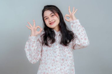 Uzun siyah saçlı, güler yüzlü ve el işaretleri gösteren neşeli, genç Asyalı kadın. Reklam ve tanıtım için mükemmel bir yüz ifadesi..
