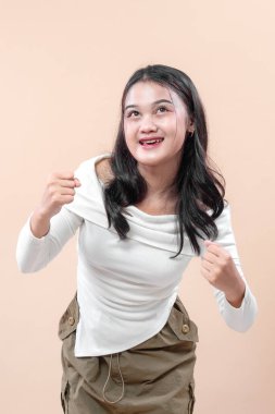 Neşeli Asyalı bir kadın yumruklarını sıkarak gülümser, enerji, güven ve iyimserliği ifade eder, bu imajı motivasyon, başarı ve yaşam tarzı kavramları için mükemmel kılar..