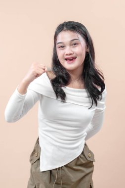 Uzun siyah saçlı neşeli bir Asyalı kadın yumruk hareketi yaparken parlak bir gülümseme sergiliyor, özgüveni, pozitifliği ve yaşam tarzı, iş hayatı ve eğitim temalarını simgeliyor..