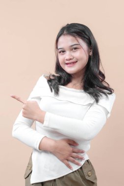 Gündelik kıyafetli gülümseyen genç bir Asyalı kadın kendine güveni olan, pozitifliğini, iletişimini ve dostça tutumunu ifade eden bir tarafı işaret ediyor..