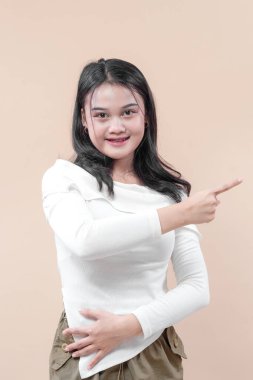 Yanları göstererek güvenle gülümseyen genç bir Asyalı kadın pozitiflik, rehberlik ve net bir yön gösteren dostane bir jest sergiliyor..