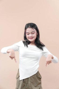 İki eliyle gülümseyen neşeli bir Asyalı kadın pozitifliğini ve dikkatini ifade ediyor. Reklam, pazarlama ve yaşam tarzı kavramları için ideal..