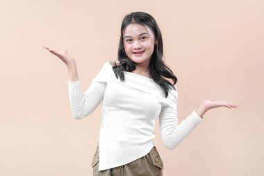 Gülümseyen Asyalı kadın iki elini birden kaldırarak olumlu, güven ve açıklık ifade ediyor. İş, yaşam tarzı veya iletişim teması için ideal..