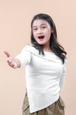 Şaşırmış Asyalı kadın elini ileri uzatıyor, şaşkınlık ve davetiyeyi ifade ediyor, fırsatları, merakı ve olumlu iletişimi simgeliyor..