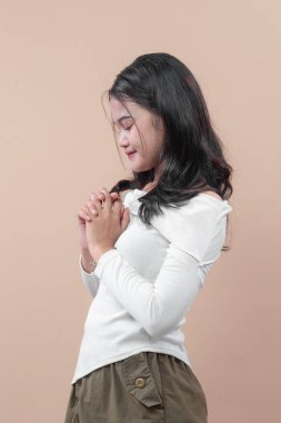 Asyalı bir kadın ellerini nazikçe gülümseyerek, minnettarlığını, sakinliğini ve pozitifliğini ifade ederek, portreyi yaşam tarzı, sağlık ve eğitim temaları için çok yönlü hale getiriyor..