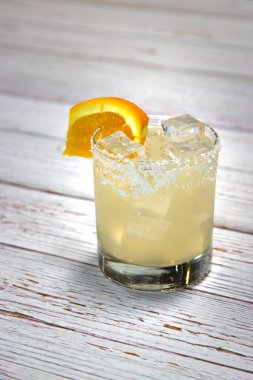 Margarita kokteyli, bir dilim turuncu garnitür ve beyaz ahşap bir yüzeye kurulmuş tuzlu jant.