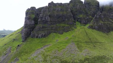 Yeşil çimenli bir yamacı olan bir dağ. Dağ kayalarla kaplı ve ona giden küçük bir patika var.