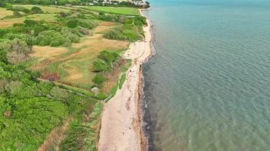 Çevrelenmiş yeşillik ve doğa ile çevrili deniz kıyısının üzerinde uçan hava.