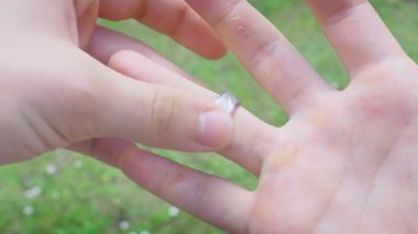 Yüzüğe Gümüş Yüzük yerleştiriliyor Parmak Beyaz Erkek El Çimen Arkasında