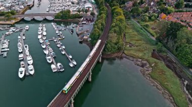 Trenin nehir köprüsünden geçişi, yaz mevsiminde Marina ile günbatımında hava aracı görüntüsü.