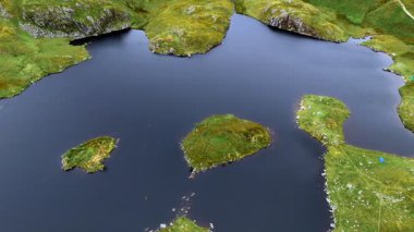 Hava aracının yakın çekim açısı alçak açıyla tarn gölünün üzerinden geçiyor. Yazın İngiltere Gölü 'ndeki bir dağın tepesinde bulutlu gökyüzü var. 